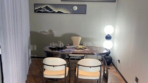 A dining area with a round table, four chairs, and a modern chandelier. - Zhihui Star Business Hotel (Chantrea)