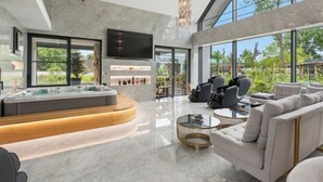 Een moderne woonkamer met een jacuzzi, grote ramen en een televisie.