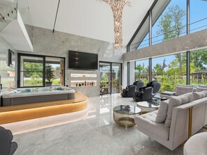 A modern living room with a hot tub, large windows, and a TV.
