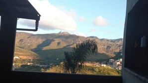 A view from a window overlooking a mountainous landscape with buildings in the distance. - Mumu's Corner (Ouro Preto)