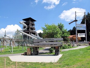 A playground with a slide, a wooden bench, and a sign with text.