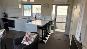 A modern kitchen with a central island, a dining area with chairs, and a view of the outside.