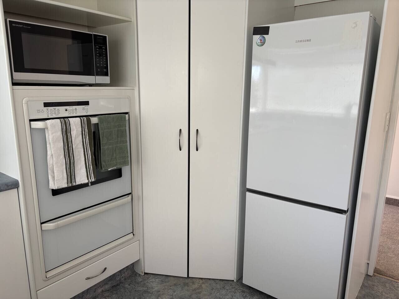 A kitchen with a microwave, oven, and a white refrigerator.