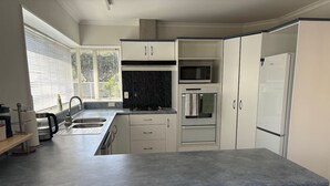 Eine moderne Küche mit weißen Schränken, einer Granit-Arbeitsplatte, einem Einbauofen und einer Mikrowelle.