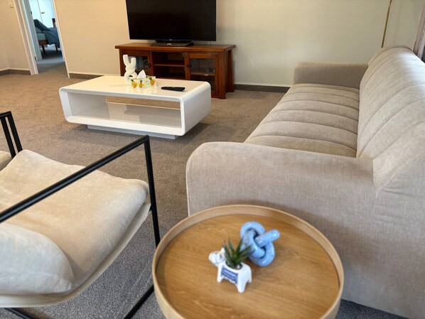 Un salon comprenant un canapé, une table basse, un meuble pour la télévision et un fauteuil.
