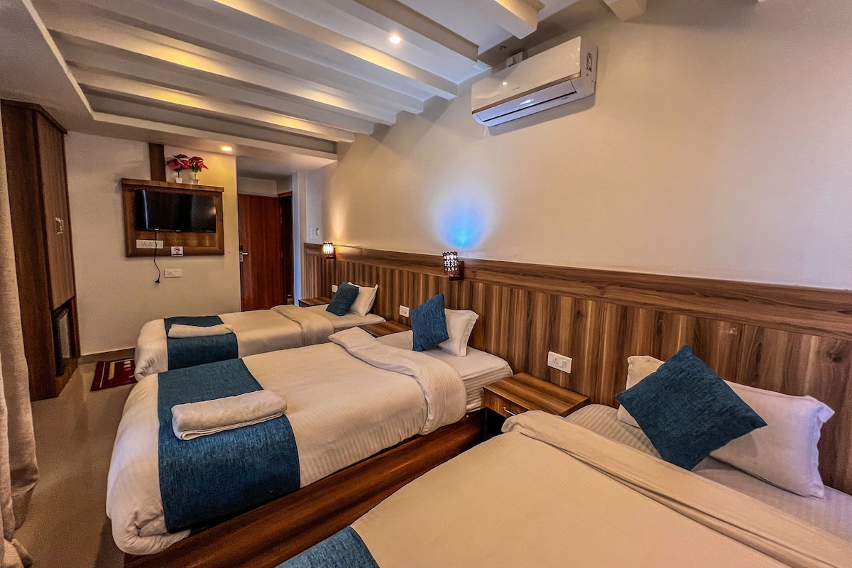 A hotel room with two beds, a TV, an air conditioner, and a wooden headboard.