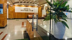 Zona de recepción de Novetel Boutique Home con interior de madera, una planta grande en maceta y un panel de vidrio.