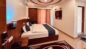 Una habitación de hotel moderna con una cama de madera, un escritorio con computadora, un televisor montado en la pared y un diseño de techo circular único.