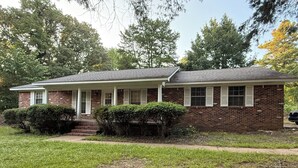 A single-story brick house with a front porch, a small front yard, and a driveway. - Charming, newly renovated 3-bedroom house just minutes from downtown Oxford. (Oxford)
