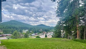 A grassy area with a view of a town and mountains in the background. - Gold Pan Hideaway (Hill City)