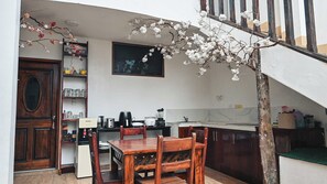 A compact kitchen with a dining area, wooden furniture, and a staircase. - Carpao Lodge (Puerto Ayora)