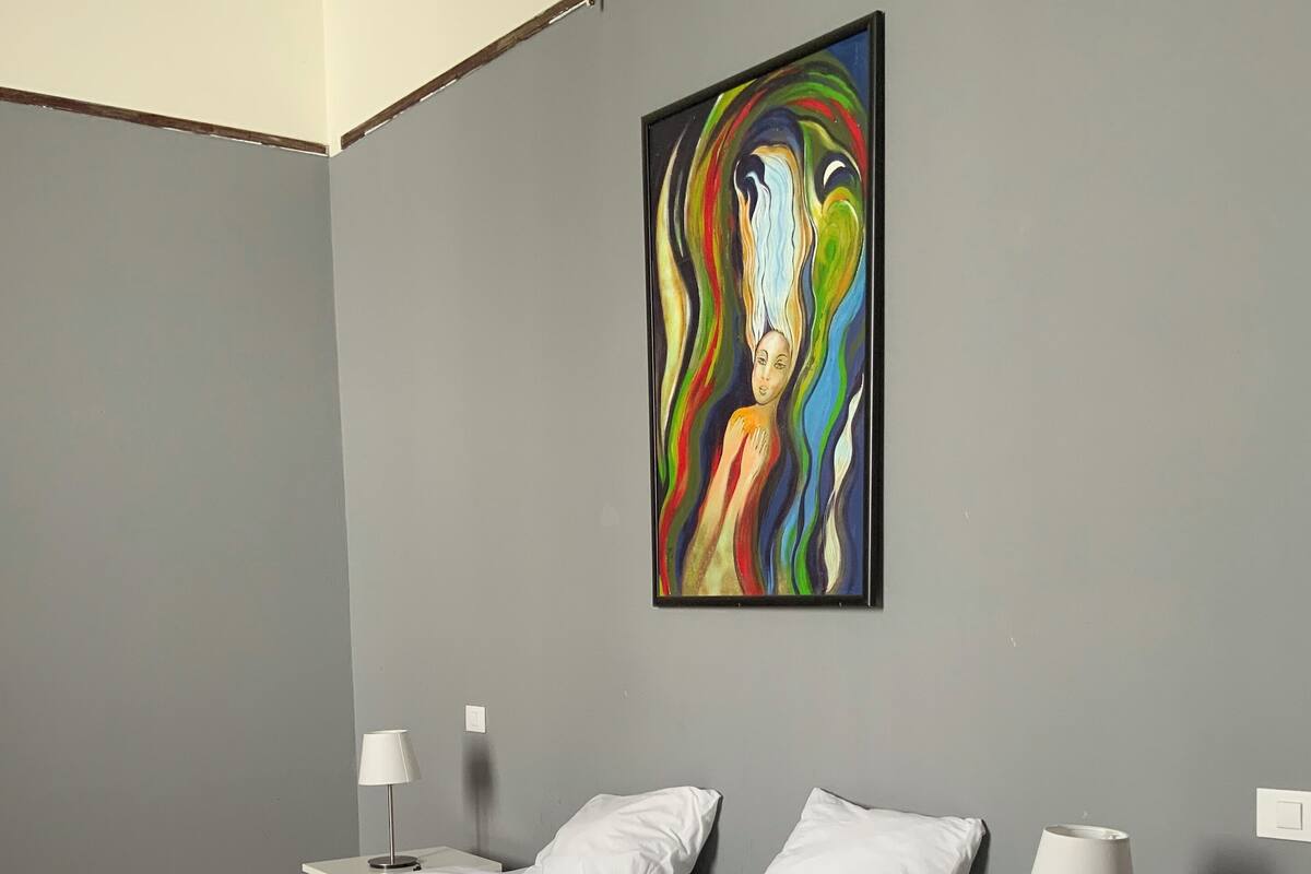 Ein Schlafzimmer mit einem Bett, Nachttischen und einem Gemälde an der Wand.