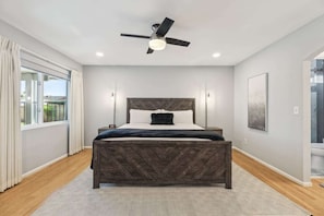 A bedroom with a herringbone-patterned bed, a ceiling fan, a large window with curtains, and a view of the outside. - Unique Luxury Daily Monthly Rent Near ASU Pet Friendly Pool (Tempe)