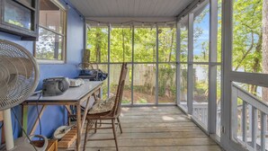 A covered porch with a table and chairs, a fan, and a window overlooking a garden. - Charming 2-bedroom cabin in beautiful Mountain Rest on Lake Becky (Mountain Rest)