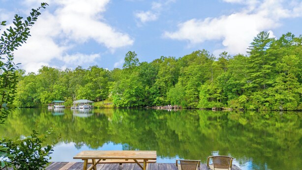 A wooden dock with a picnic table and two chairs, overlooking a calm lake surrounded by dense green trees. - Charming 2-bedroom cabin in beautiful Mountain Rest on Lake Becky (Mountain Rest)