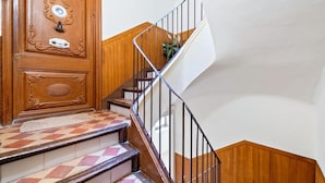 Un escalier en bois avec des marches à carreaux, une main courante et une porte ornée de sculptures complexes.