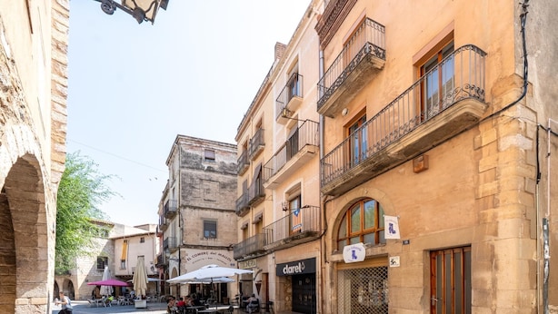 Une rue pavée avec des tables et des chaises installées à l’extérieur d’un café.
