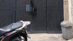 En sort metalport med et skilt over, en motorcykel foran og en skraldespand til højre.