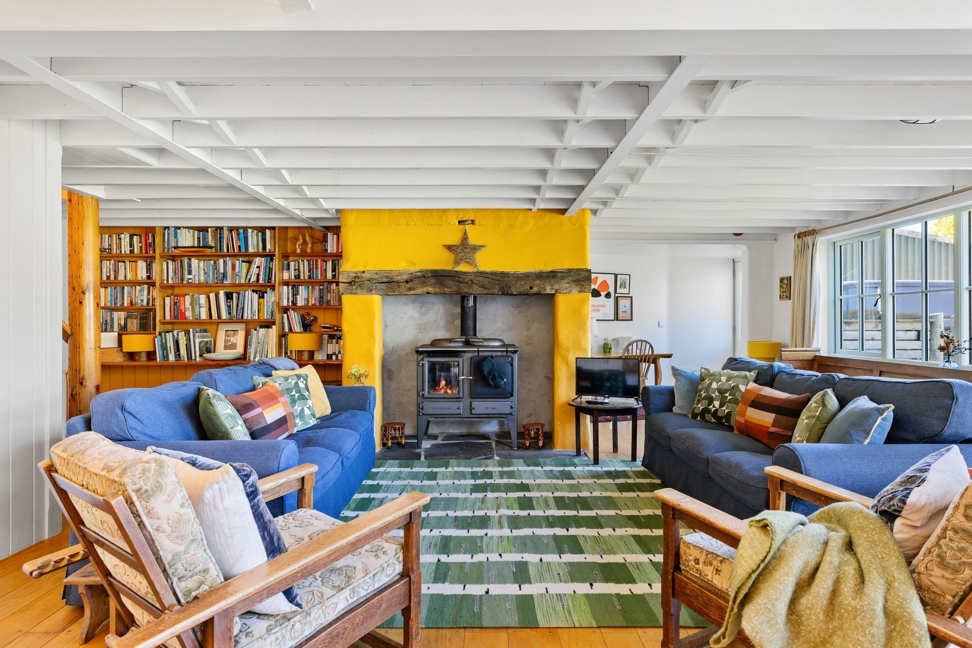 A cozy living room with a fireplace, bookshelves, and comfortable seating.