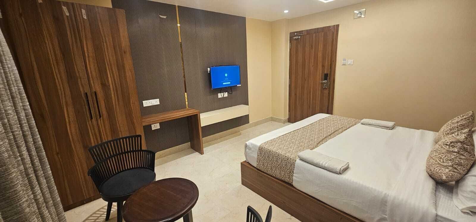 Una camera d'albergo con un letto, una scrivania, una sedia, una TV e un armadio.