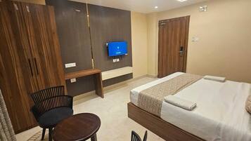 Una camera d'albergo con un letto, una scrivania, una sedia, una TV e un armadio.