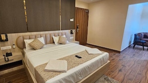 Una habitació d'hotel amb un llit gran, un capçal de fusta, una taula de nit amb un telèfon i una porta amb maneta.