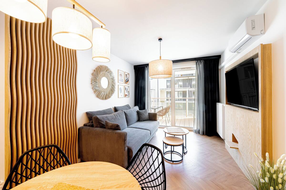 Ein modernes Wohnzimmer mit einer Couch, Sesseln, einem Esstisch und einem Fernseher.
