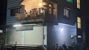Ein mehrstöckiges Gebäude mit einem Balkon im oberen Geschoss, einer Garage im Erdgeschoss und einem Schild mit Schrift in einer nicht-englischen Sprache.