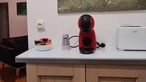 Una cocina con encimera blanca, un hervidor rojo, un tostador blanco y un cuadro en la pared.