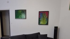 Una sala de estar moderna con un sofá negro, una mesa de centro de madera y dos obras de arte enmarcadas en la pared.