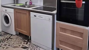 Una cocina compacta equipada con lavadora, lavavajillas, microondas y horno.