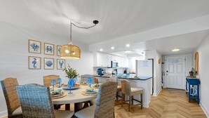A dining area with wicker chairs, a round table, and a hanging light fixture.