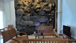 A room with a stone wall, wooden furniture, and a television. - Benada Piyungan Yogyakarta by ABM (Berbah)