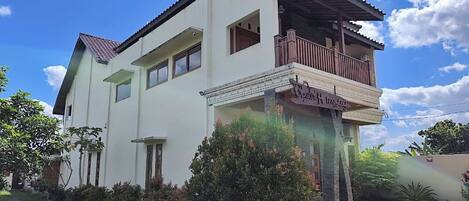 Um edifício de dois andares com varanda no segundo andar, alpendre coberto e uma placa com a inscrição