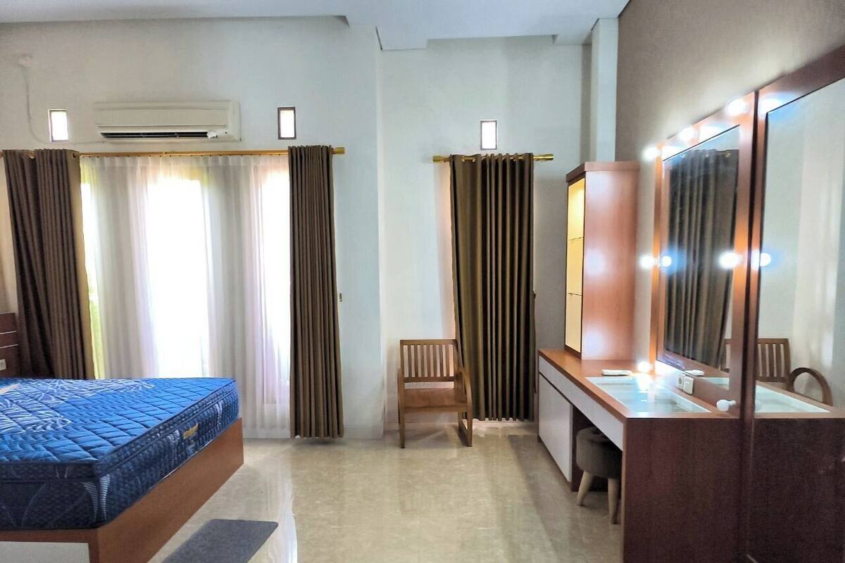 Ein Hotelzimmer mit einem Bett, einem Schreibtisch mit Spiegel, einem Stuhl und einem Schminktisch mit Spiegel.