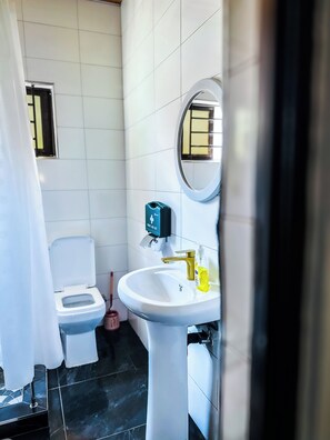 A bathroom with a toilet, a sink with a mirror, and a first aid kit on the wall.