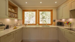 Una cocina con dos ventanas, un fregadero y armarios.