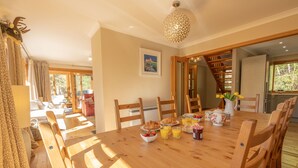 Comedor con mesa de madera, sillas, alimentos para el desayuno y una escalera que lleva a otra habitación.