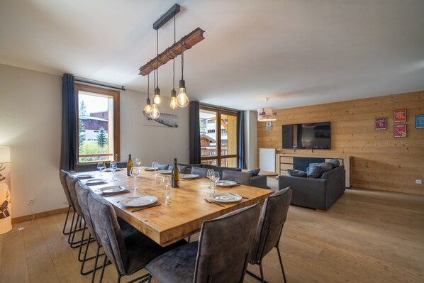 A modern dining area with a wooden table, chairs, and hanging light fixtures.