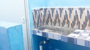 A bathroom with a blue wall, a patterned sink, and a tiled floor. - ZELLA KOST & HOMESTAY (Labuan Bajo)