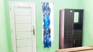 A room with a bed, a desk, a chair, a wardrobe, and a door. - ZELLA KOST & HOMESTAY (Labuan Bajo)