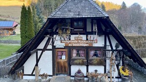 A traditional half-timbered building with a steeply pitched roof, a wooden door, and a sign indicating it is a guesthouse. - NEW: Exclusive Waldliebe apartment with indoor pool and sauna (Schonach im Schwarzwald)