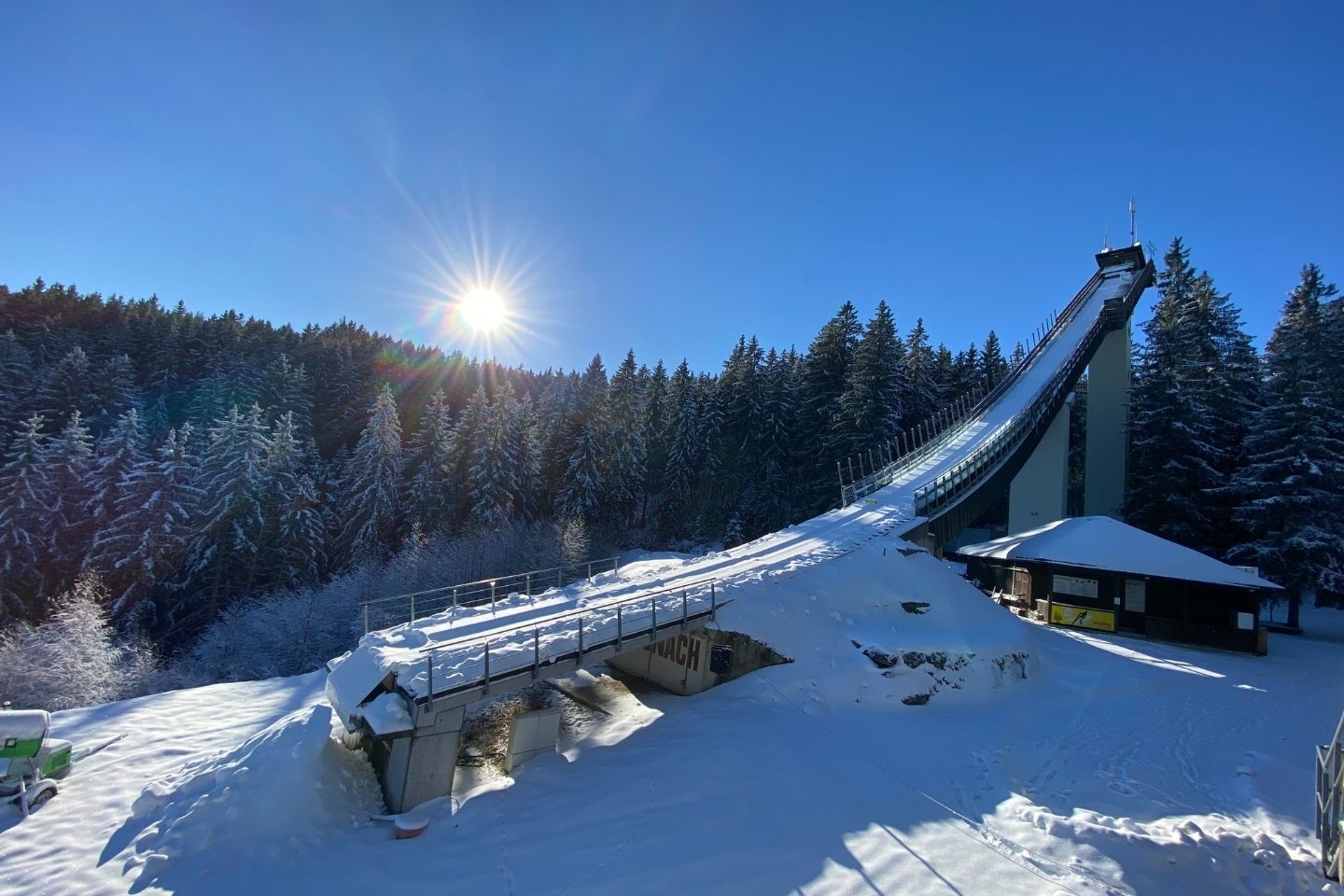A snow-covered ski lift in a forested area with a clear sky.