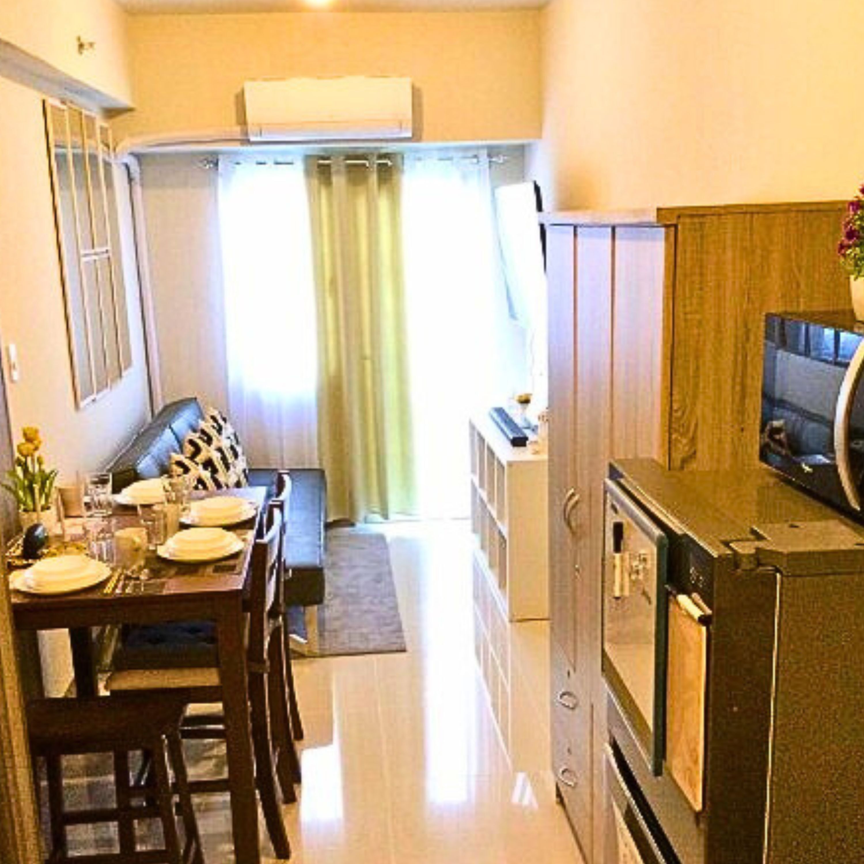 Una cocina compacta con comedor, horno empotrado y televisor.