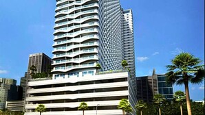 A tall, modern skyscraper with a unique curved facade and multiple balconies. - Rent Xpress Online US Embassy (Pasay)