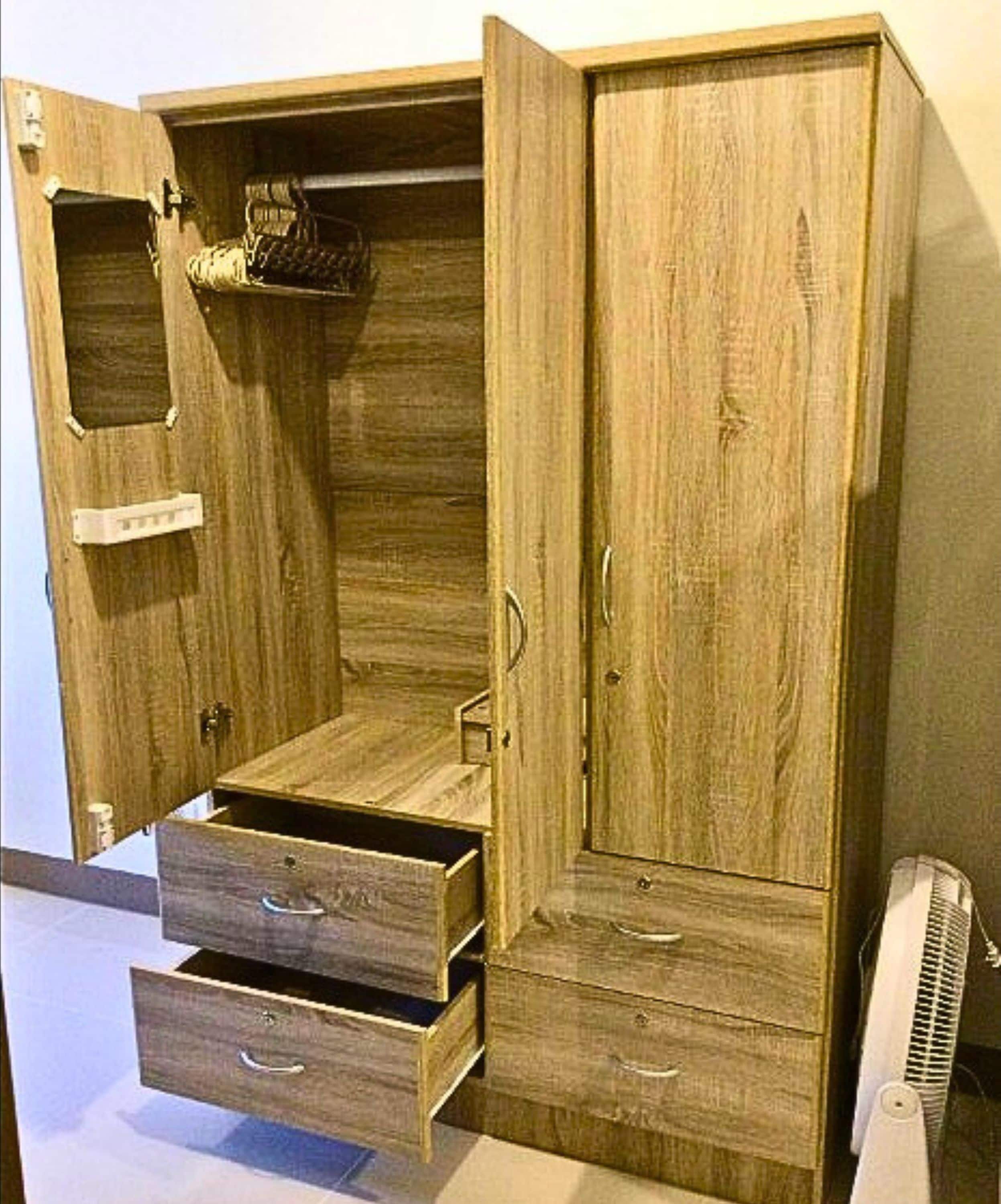 A wooden wardrobe with multiple compartments, including a hanging section and drawers.