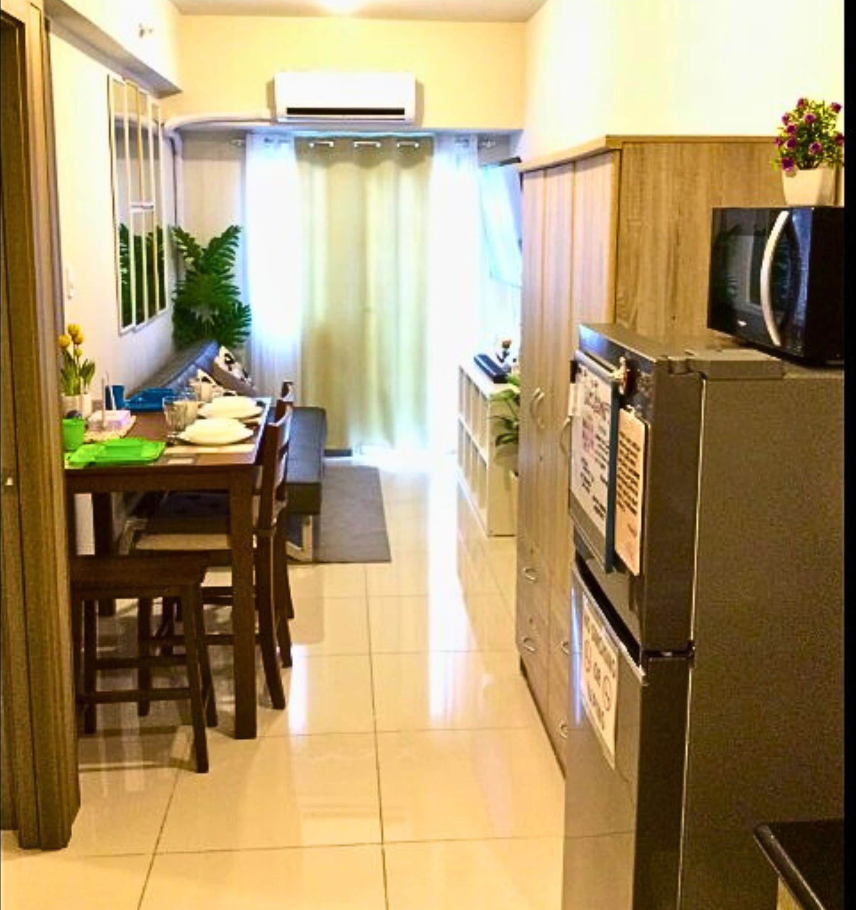 A compact kitchen with a refrigerator, microwave, and a dining area with chairs and a table.