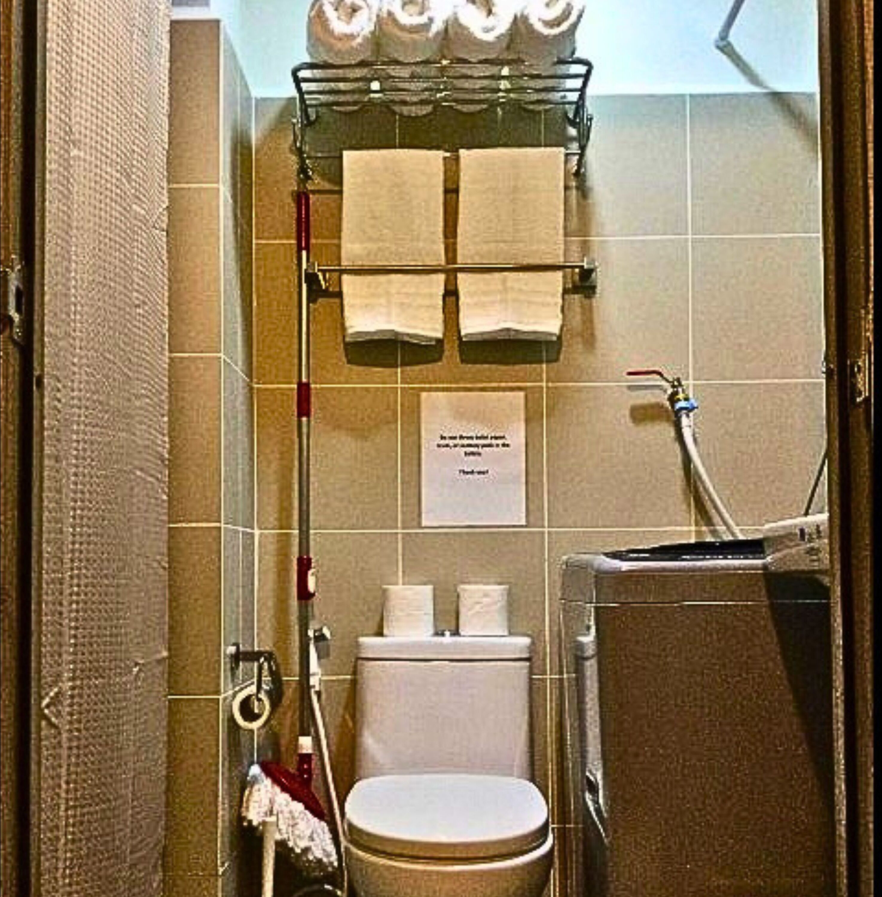 Une salle de bain équipée de toilettes, d’un porte-serviettes et d’un sèche-mains.