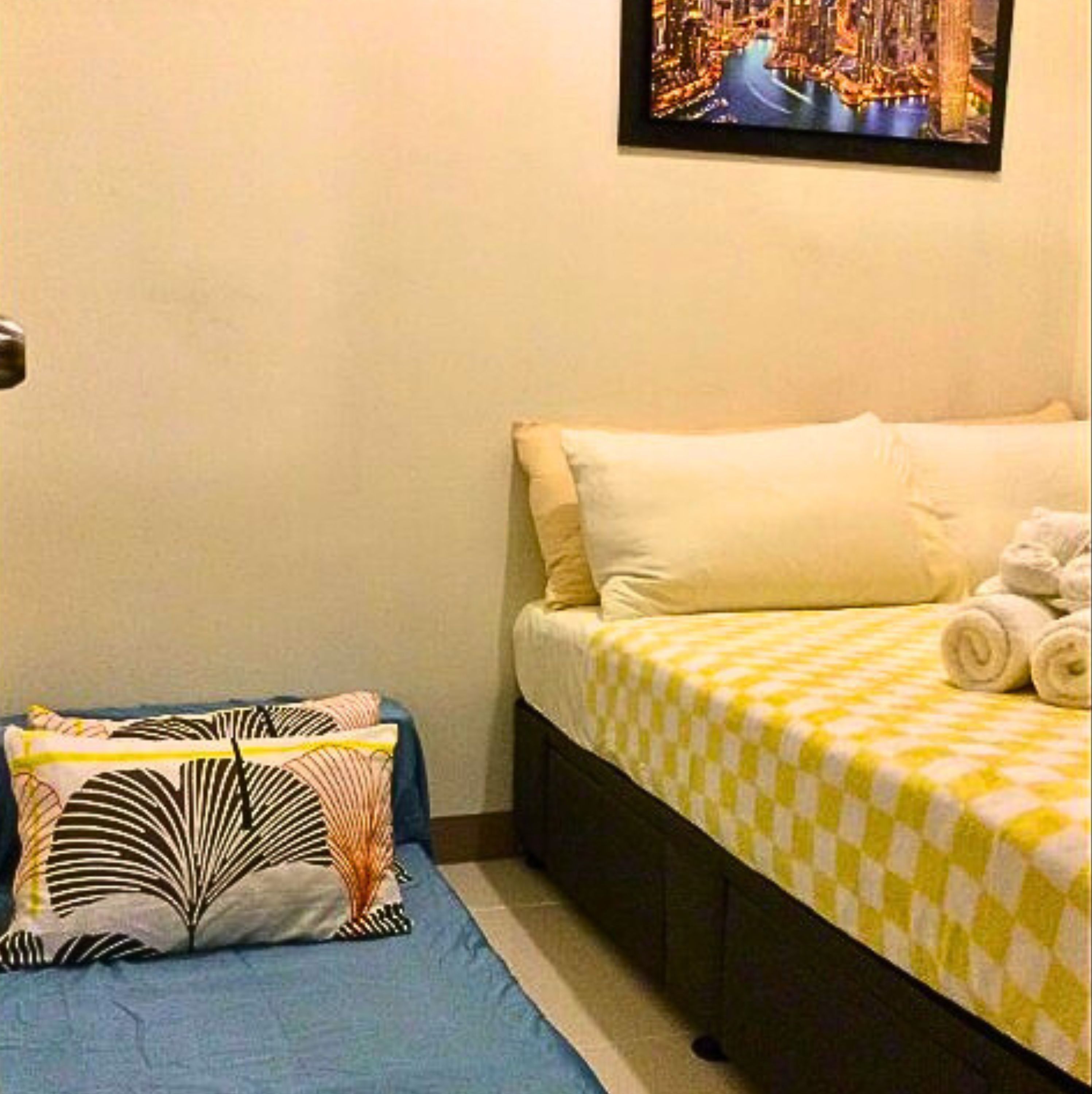 Een hotelkamer met een bed, kussens, een blauwe bank en een stadslandschap op de muur.