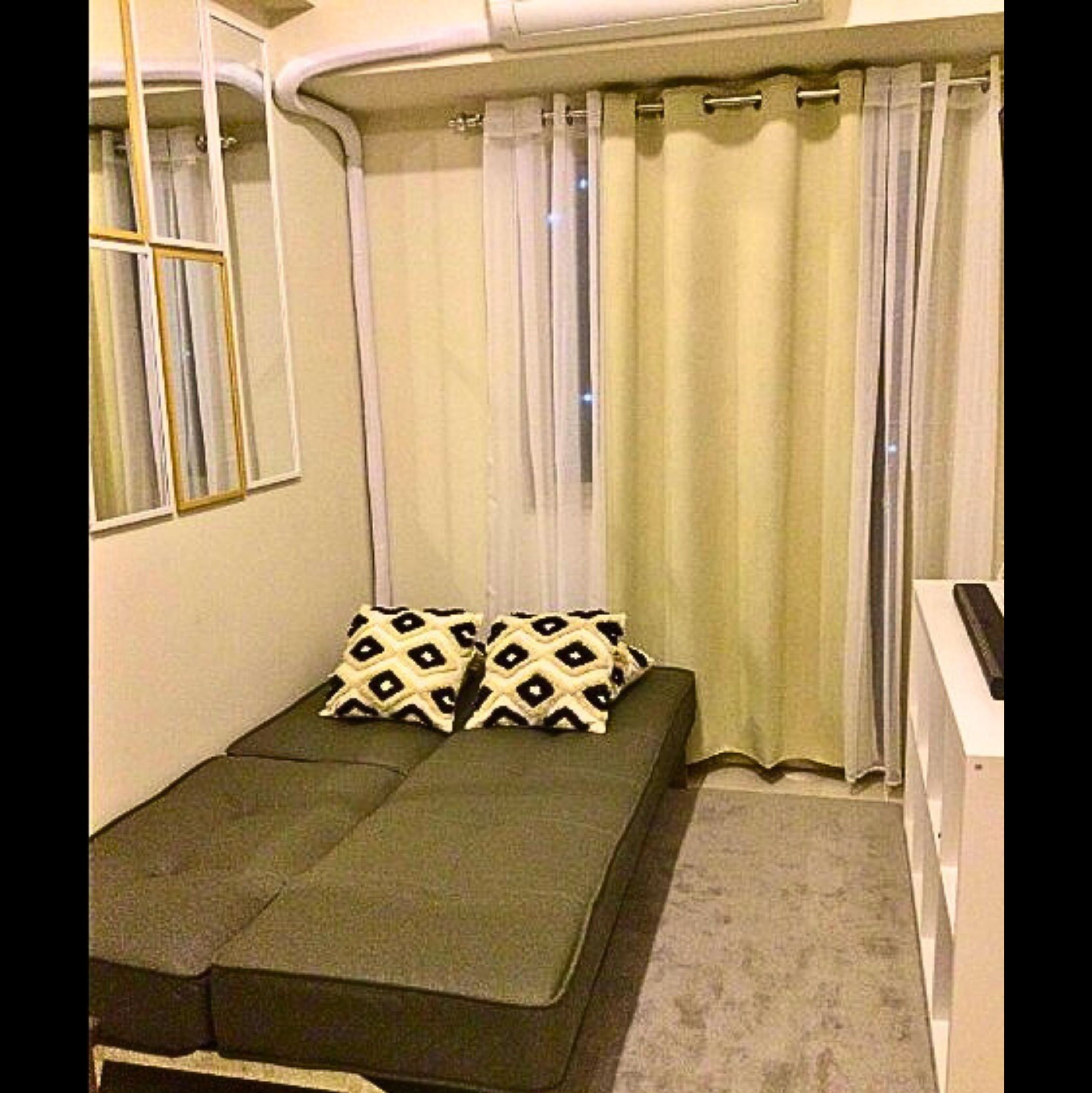 A small room with a single bed, a window with curtains, and a small desk.